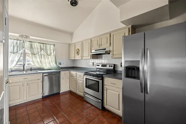 a kitchen with stainless steel appliances granite countertop a stove a sink and a refrigerator