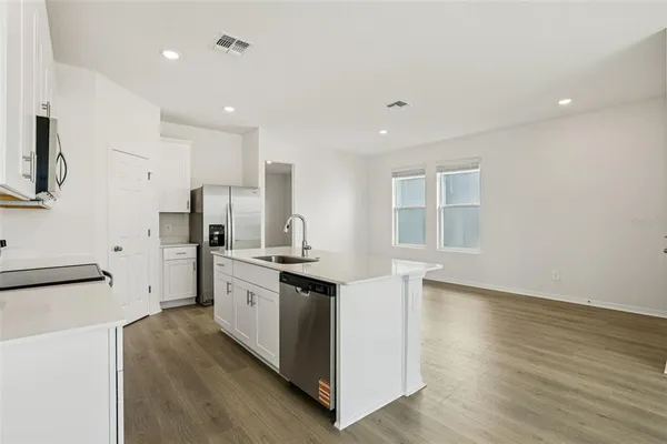 a kitchen with stainless steel appliances a stove top oven a sink a refrigerator a window