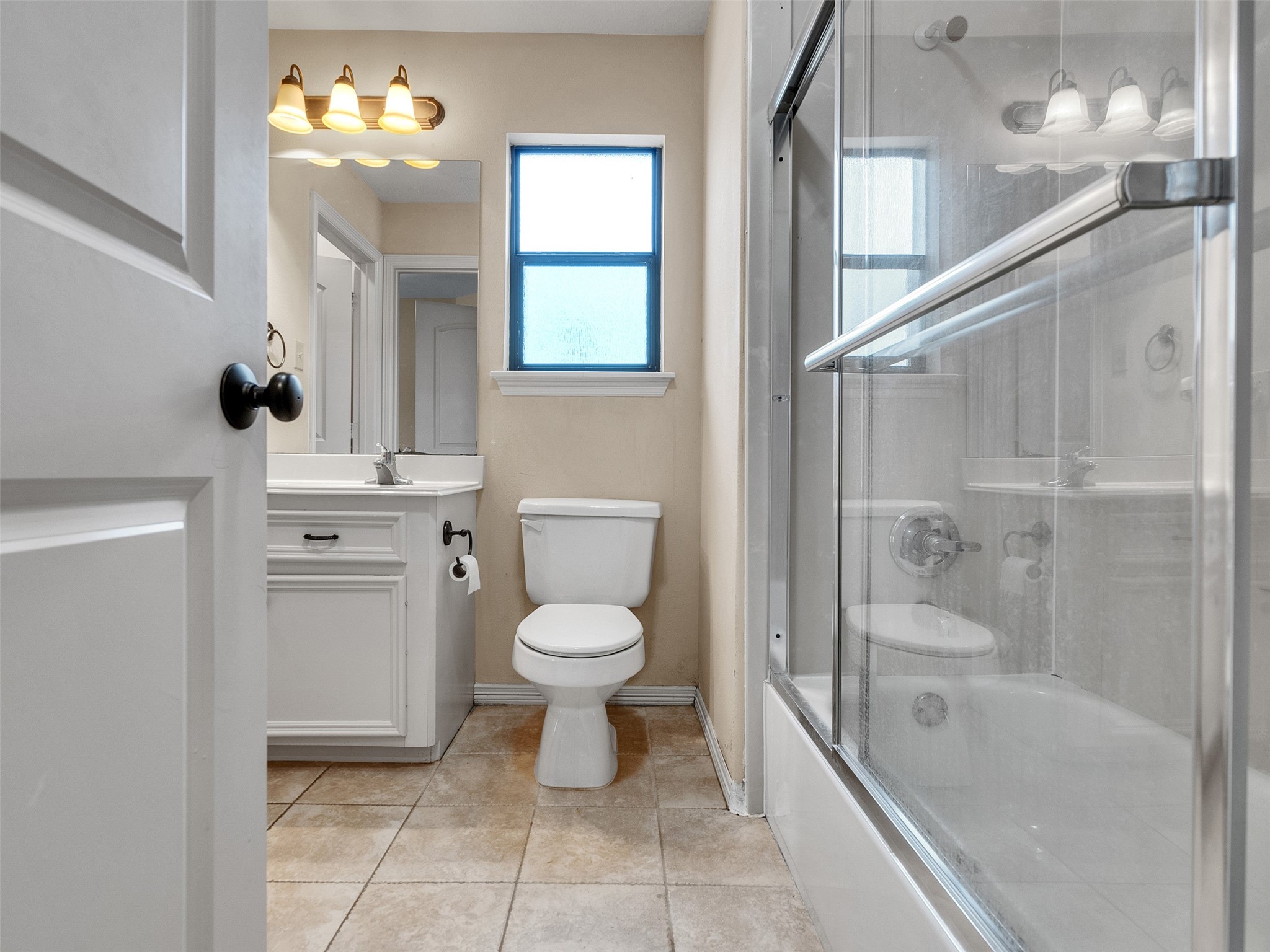 6914 Sandwedge Point Court Spring, TX 77389 - Photo 37 of 50 This bathroom features a clean, modern design with a tiled floor, a glass-enclosed bathtub, a white vanity, and a window for natural light.