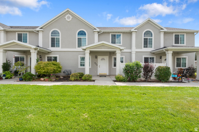 Colonial-style house featuring stucco siding and a front yard