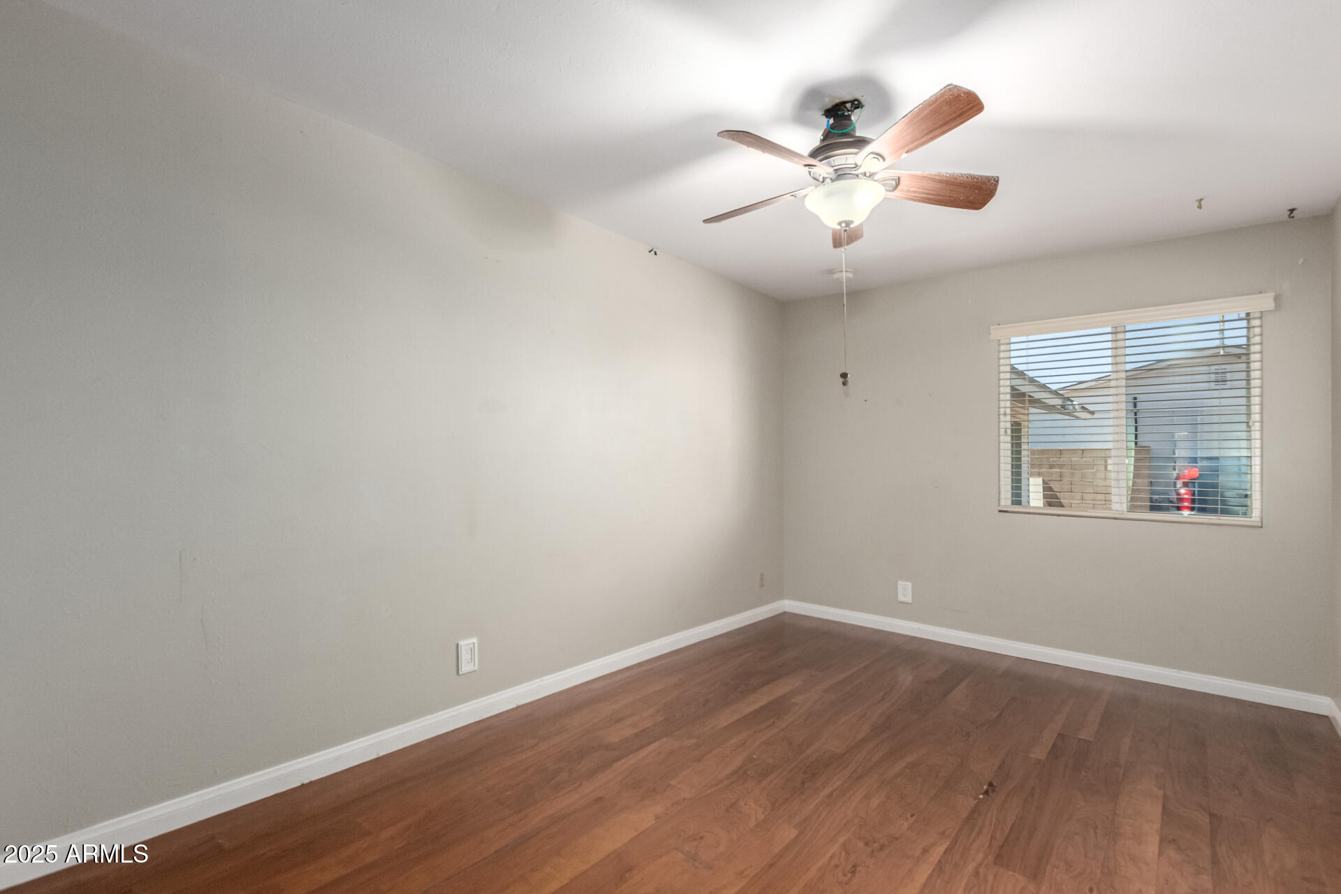 3045 East Cholla Street Phoenix, AZ 85028 - Photo 11 of 23 an empty room with wooden floor chandelier fan and windows