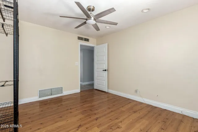 an empty room with wooden floor and a ceiling fan
