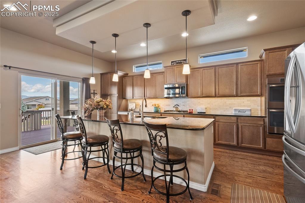 3718 Sky Rim Court Colorado Springs, CO 80908 - Photo 18 of 49 a kitchen with stainless steel appliances granite countertop a kitchen island a stove a table and chairs in it