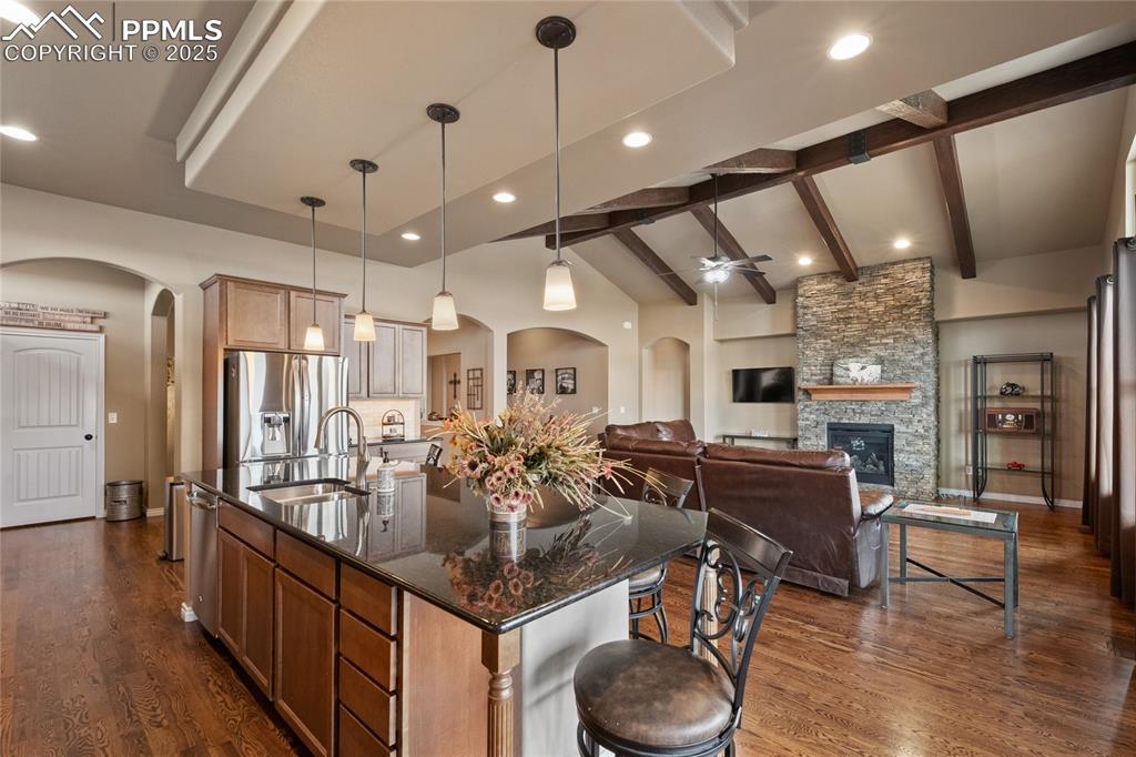 3718 Sky Rim Court Colorado Springs, CO 80908 - Photo 21 of 49 a kitchen with stainless steel appliances kitchen island granite countertop a table chairs in it and wooden floors