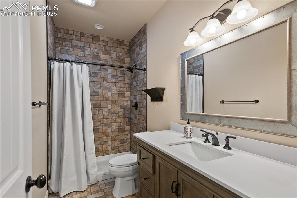 3718 Sky Rim Court Colorado Springs, CO 80908 - Photo 42 of 49 a bathroom with a sink a toilet a mirror and shower curtain