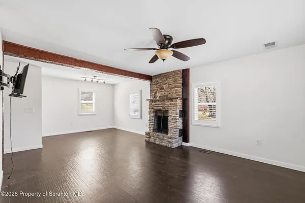 a view of a livingroom with wooden floor a ceiling fan and a window