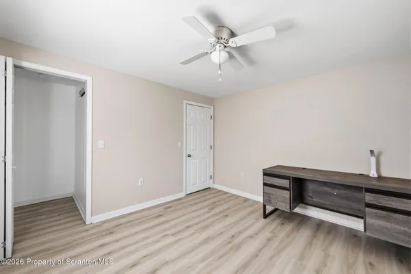 an empty room with wooden floor fan and windows