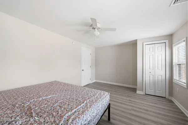 an empty room with wooden floor fan and windows