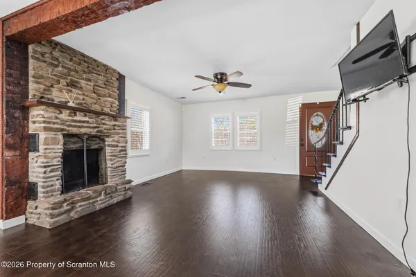 a view of a livingroom with wooden floor a fireplace and windows