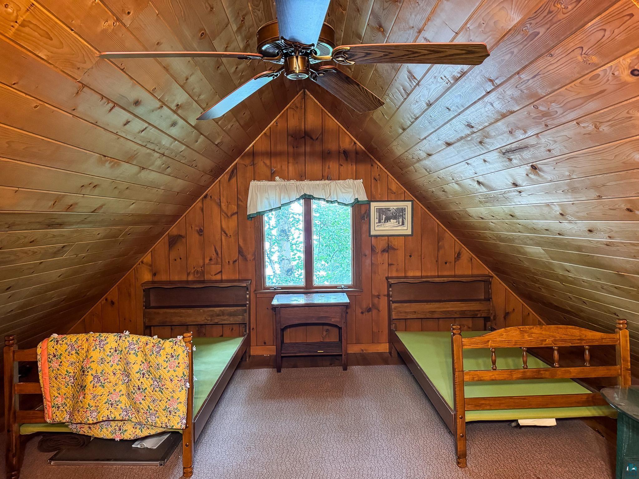 465 South Gunflint Lake Road Grand Marais, MN 55604 - Photo 40 of 46 Room featuring sloped wood-paneled walls and ceiling, a central window with exterior tree views, and a ceiling fan