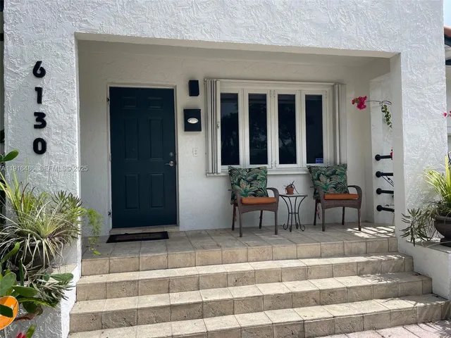 a view of a entryway door of the house with potted plants and brick walls