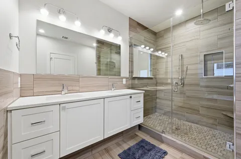 a bathroom with a double vanity sink mirror and shower