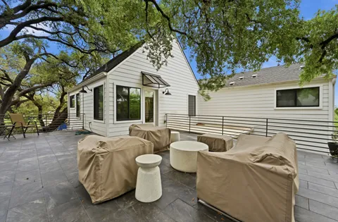 a view of a patio with couches table and chairs and wooden fence