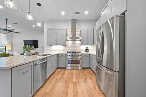 a kitchen with stainless steel appliances a refrigerator sink and wooden floor