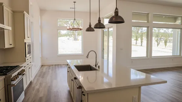 a kitchen with stainless steel appliances granite countertop a sink a stove and wooden floor