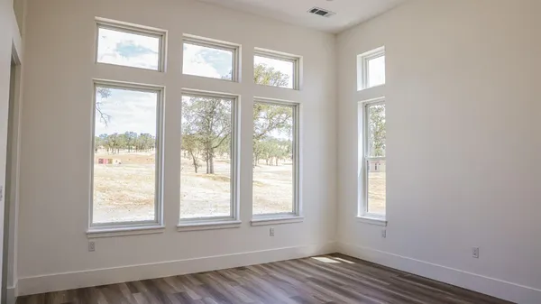an empty room with wooden floor and windows