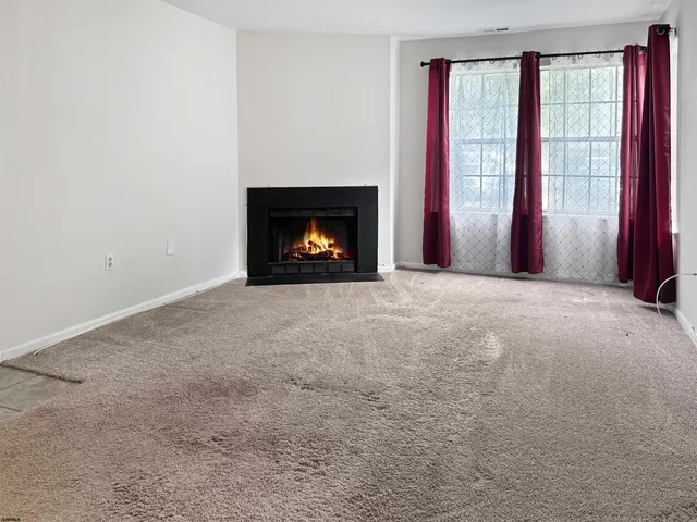 an empty room with windows and fireplace