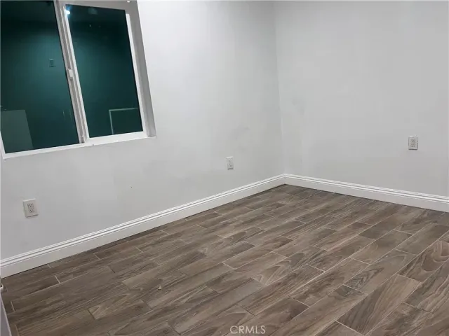 an empty room with wooden floor and mirror