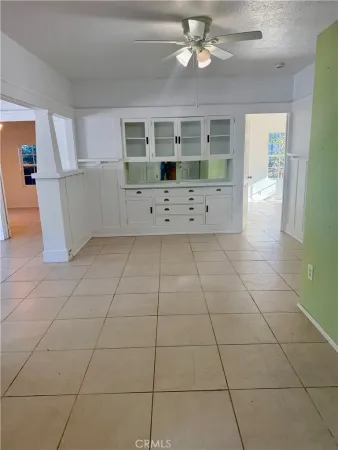 a view of a livingroom with furniture cabinet a flat screen tv and a chandelier