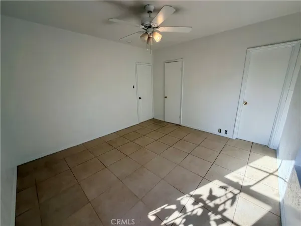 an empty room with windows and ceiling fan