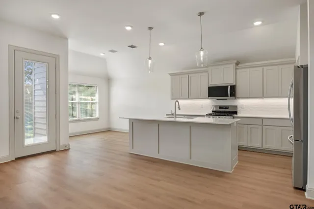 a kitchen with kitchen island granite countertop a sink cabinets and wooden floor