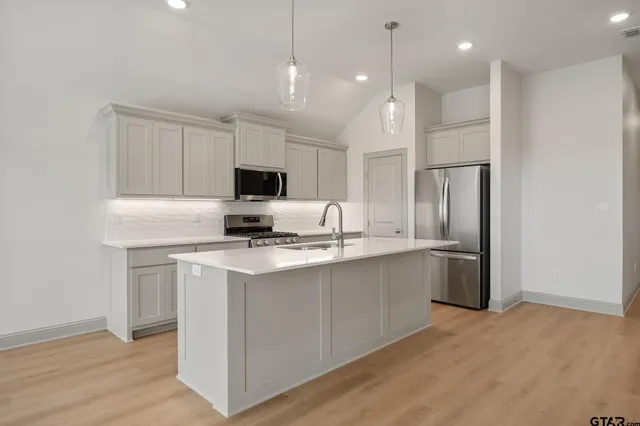 a kitchen with stainless steel appliances granite countertop a refrigerator a stove a sink and a microwave