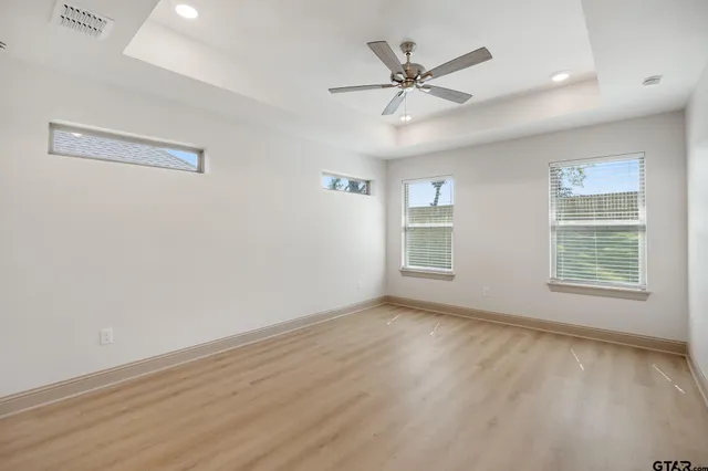 a view of an empty room with a window and wooden floor