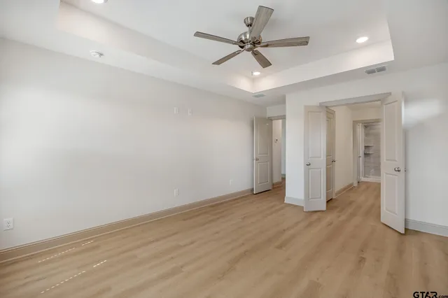 an empty room with wooden floor and ceiling fan