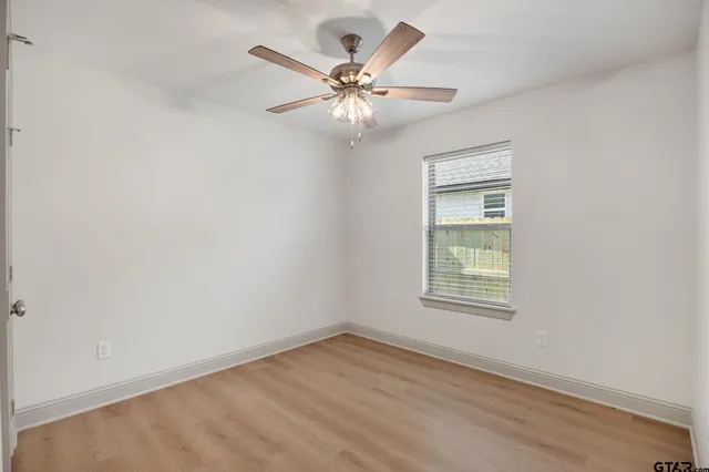 an empty room with a window and a fan
