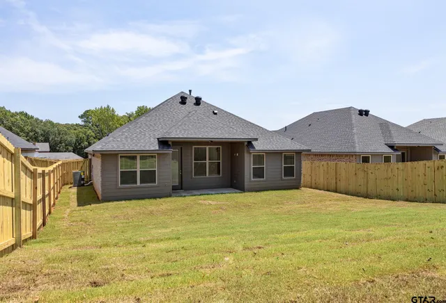 a front view of house with yard and trees in the background
