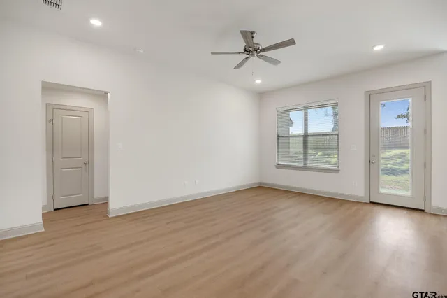 a view of an empty room with a window and wooden floor
