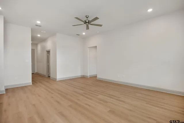 an empty room with wooden floor and a ceiling fan
