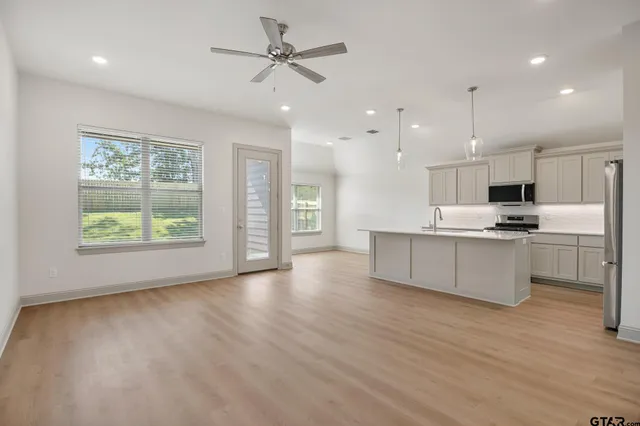 a large kitchen with stainless steel appliances kitchen island a large counter top and a wooden floors
