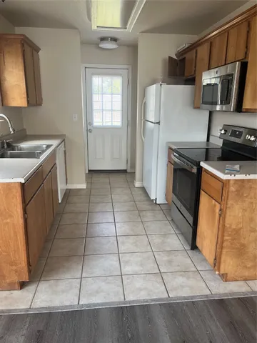 a kitchen with granite countertop a refrigerator and a stove top oven