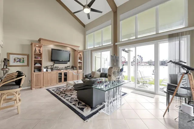 a living room with furniture a flat screen tv and a floor to ceiling window