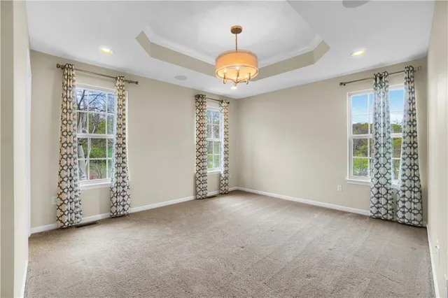 an empty room with windows and chandelier fan