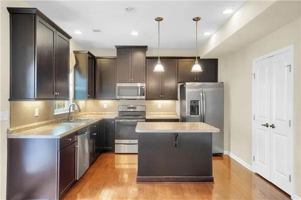 a large kitchen with a large counter top a sink stainless steel appliances and cabinets
