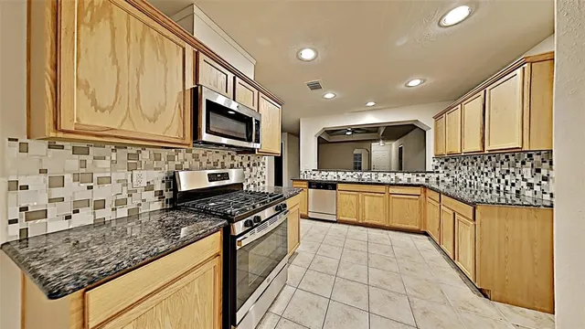 a large kitchen with stainless steel appliances granite countertop a stove sink and cabinets
