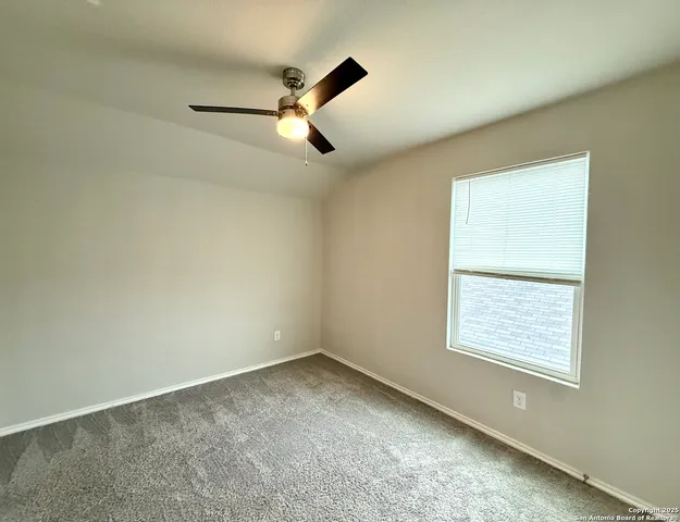 an empty room with a window and a ceiling fan