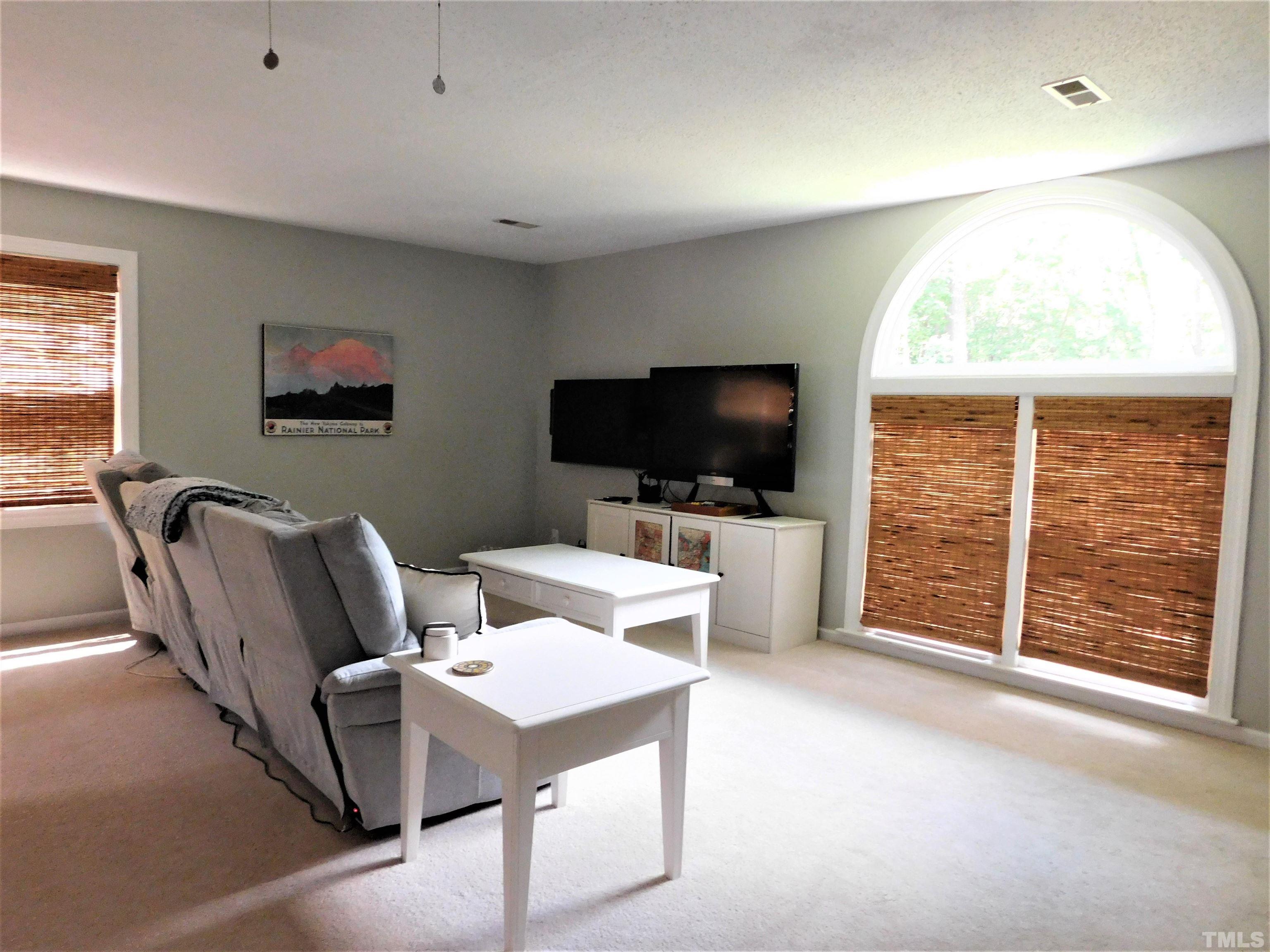 11417 Pacesferry Drive Raleigh, NC 27614 - Photo 25 of 39 a living room with furniture a flat screen tv and a floor to ceiling window