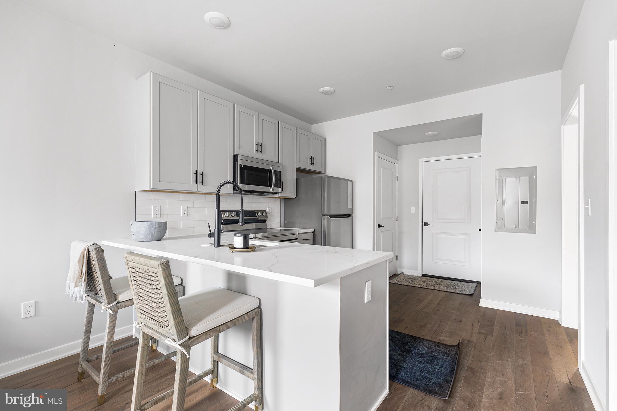 5542-44 Ridge Avenue, Unit 314 Philadelphia, PA 19128 - Photo 5 of 19 a kitchen with kitchen island a stove a table and chairs