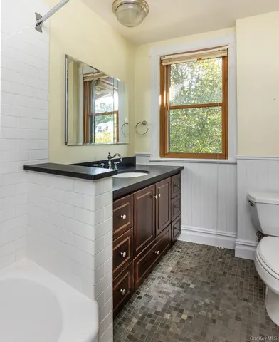 a bathroom with a granite countertop sink a toilet and window