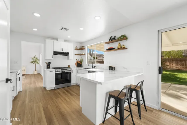 a kitchen with stainless steel appliances granite countertop white cabinets a sink a stove a refrigerator and white cabinets