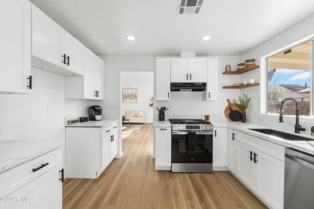 a kitchen with stainless steel appliances granite countertop a sink a stove and a window