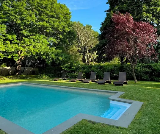 a view of a swimming pool with lawn chairs and plants