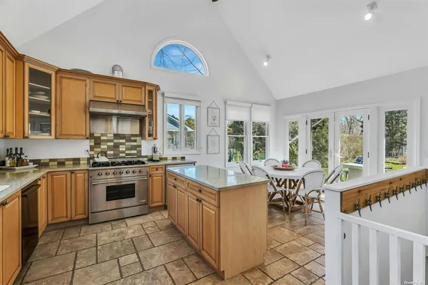 a kitchen with stainless steel appliances granite countertop a stove top oven a sink dishwasher a dining table and chairs with wooden floor