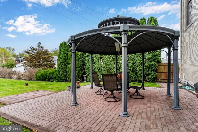 a backyard of a house with table and chairs plants and large tree