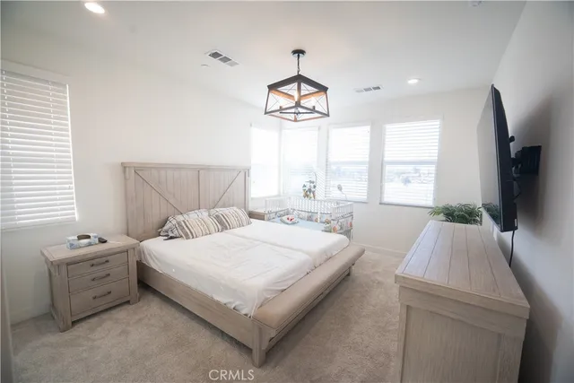 a bedroom with a bed a flat screen tv and a large window