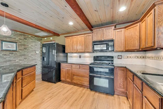 a kitchen with stainless steel appliances granite countertop wooden cabinets stove top oven and sink