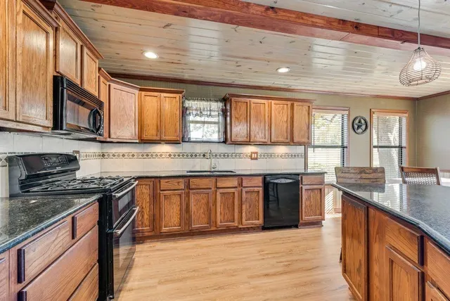 a kitchen with stainless steel appliances granite countertop wooden cabinets a stove top oven a sink and dishwasher